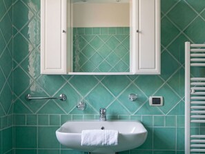 Ein Badezimmer mit einem weißen Waschbecken, einem Spiegel darüber und einem Handtuch an der Wand.
