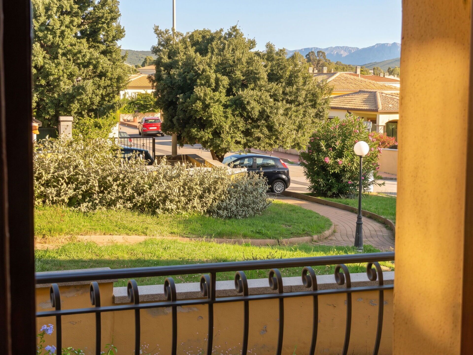 Una calle residencial con coches aparcados, una curva y zonas verdes.