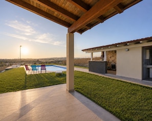 Eine moderne Außenpatio mit Pool, Sitzgelegenheiten und Blick auf die Landschaft.