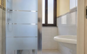 Ein Badezimmer mit Duschkabine aus Glas, einer weißen Badewanne und gefliesten Wänden.