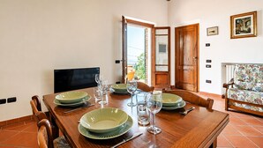 Uma sala de jantar com uma mesa de madeira posta para quatro pessoas, rodeada por cadeiras.