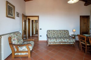Ein Wohnzimmer mit zwei Holzsofas, einem Esstisch mit Stühlen und einer Tür zu einem anderen Raum.