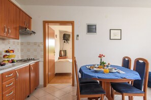 Een kleine keuken met een eethoek, een klein televisietoestel aan de muur en een ingelijste foto.