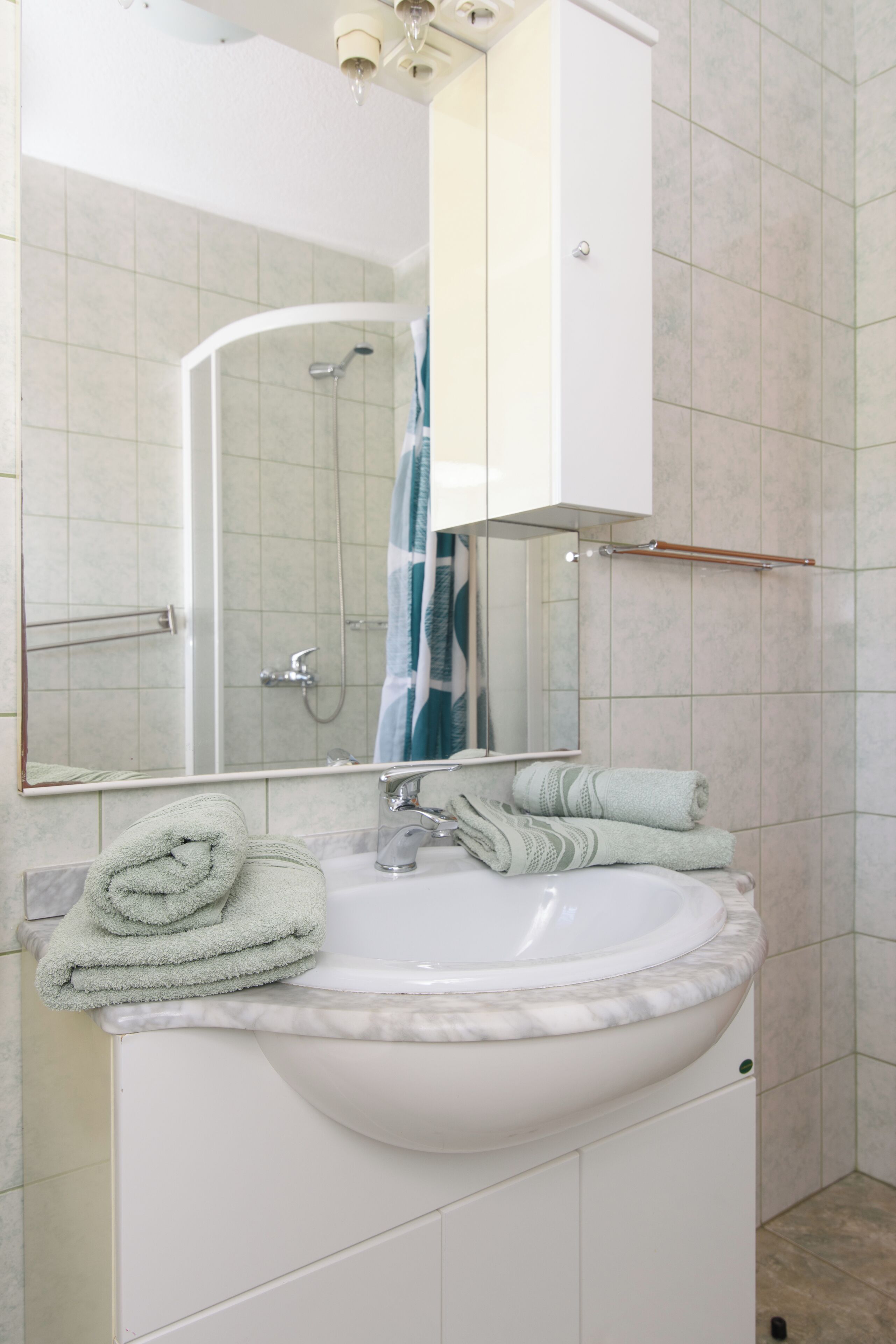 A bathroom with a white sink, a mirror, and a shower.