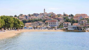 A coastal town with buildings, a beach, and a body of water. - A1 – apartment Robi with shared heated pool & balcony, near the beach (Seget Vranjica)