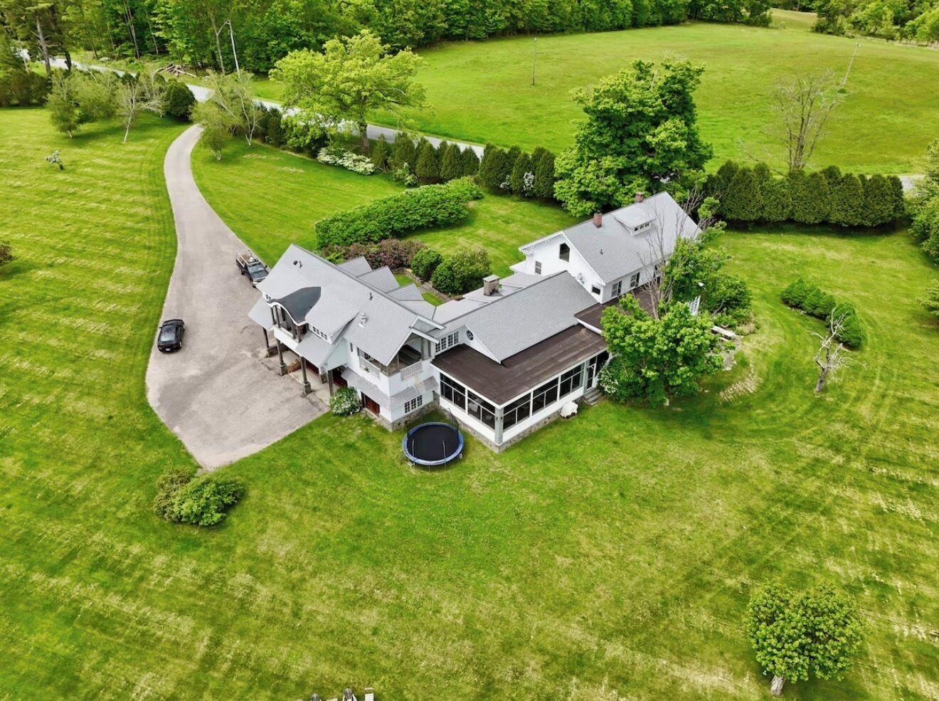 A large, two-story house with a driveway and a trampoline in the front yard.