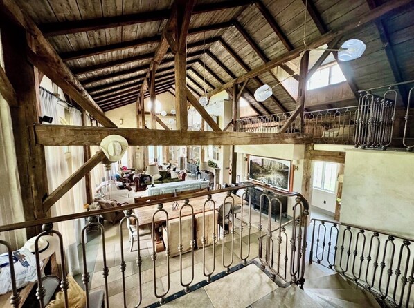 A rustic interior with a wooden ceiling, metal railings, and a dining area with a table and chairs.