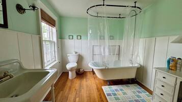 Une salle de bain avec une baignoire, des toilettes, un lavabo et une fenêtre.