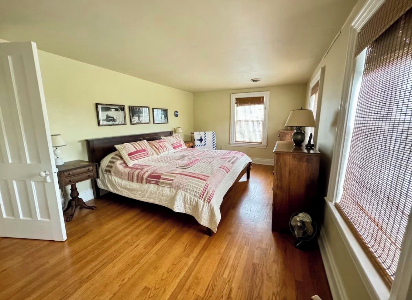 A bedroom with a bed, bedside table, lamp, and a window with blinds.