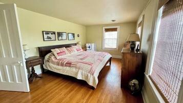 A bedroom with a bed, bedside table, lamp, and a window with blinds.