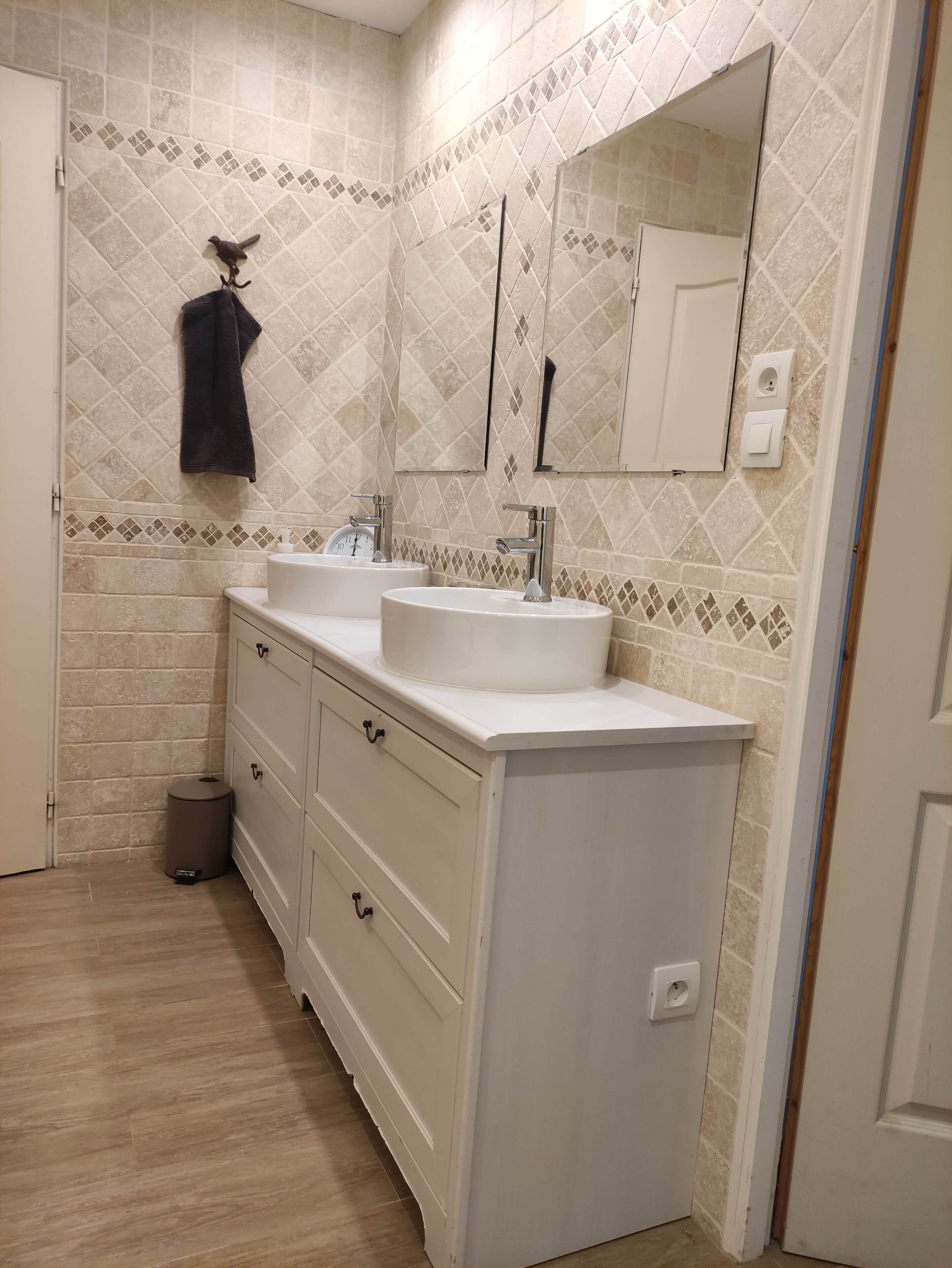 Un baño con dos lavamanos, un espejo y un perchero para toallas.