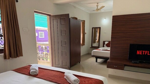 Habitación de hotel con cama, televisor, armario y vista al exterior.