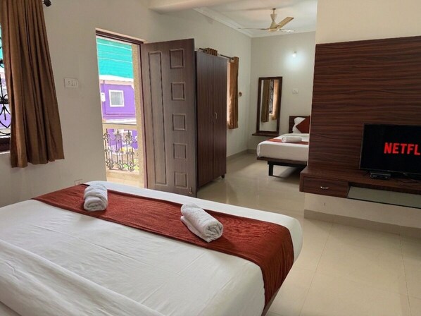 Habitación de hotel con cama, televisor, armario y vista al exterior.