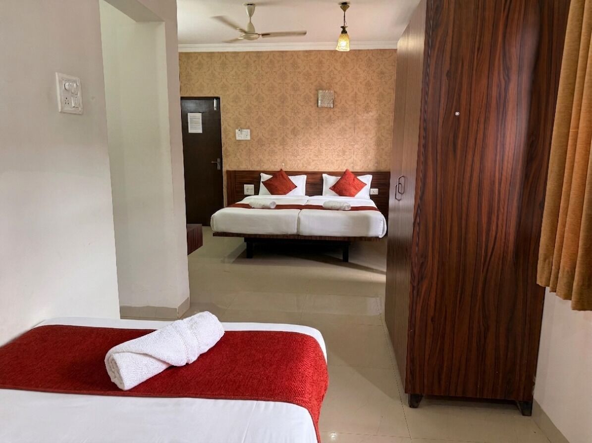 A hotel room with two beds, a wooden wardrobe, and a ceiling fan.