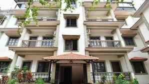 Un edificio de varios pisos con balcones, una entrada cubierta y un tejado de tejas.