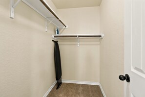 A corner of a room with a white door, a black coat hanging on a hook, and a white shelf with a wooden rod. - 16801-SD2 • Spacious Family Townhome•3BR• Backyard• Fast Wi-Fi (Selma)