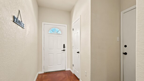 A hallway with a white door, a welcome sign, and a textured wall. - SD2 • Spacious Family Townhome•3BR• Backyard• Fast Wi-Fi (Selma)