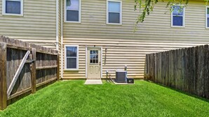A residential backyard with a wooden fence, a door, and an air conditioning unit. - SD2 • Spacious Family Townhome•3BR• Backyard• Fast Wi-Fi (Selma)