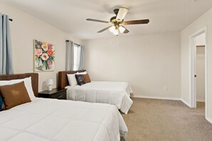 A hotel room with two beds, a ceiling fan, a painting, and a door. - SD2 • Spacious Family Townhome•3BR• Backyard• Fast Wi-Fi (Selma)