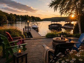 A lakeside patio with outdoor seating, a dock, and boats.