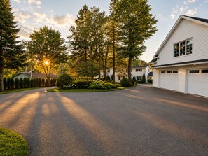 A residential driveway leading to a two-story house with a garage.