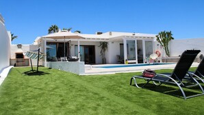 Een modern huis met een zwembad, terras en een verzorgd gazon.