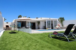 Ein modernes Haus mit Pool, Außenbereich und gepflegtem Rasen.