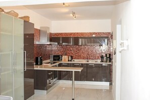 Eine moderne Küche mit Kochinsel, Edelstahlgeräten und einer Mosaik-Spritzschutzwand.