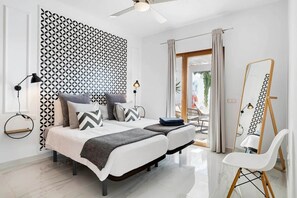 A modern bedroom with a bed, bedside lamps, a mirror, and a view of the outdoors. - El Ancla - Luxury Villa with great View (Playa Blanca)