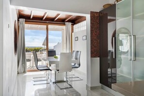 Eine moderne Küche mit einem Kühlschrank mit Glastür, einem Essbereich mit Tisch und Stühlen sowie Blick ins Freie.