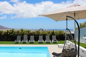 A pool area with lounge chairs and a view of the city. - El Ancla - Luxury Villa with great View (Playa Blanca)