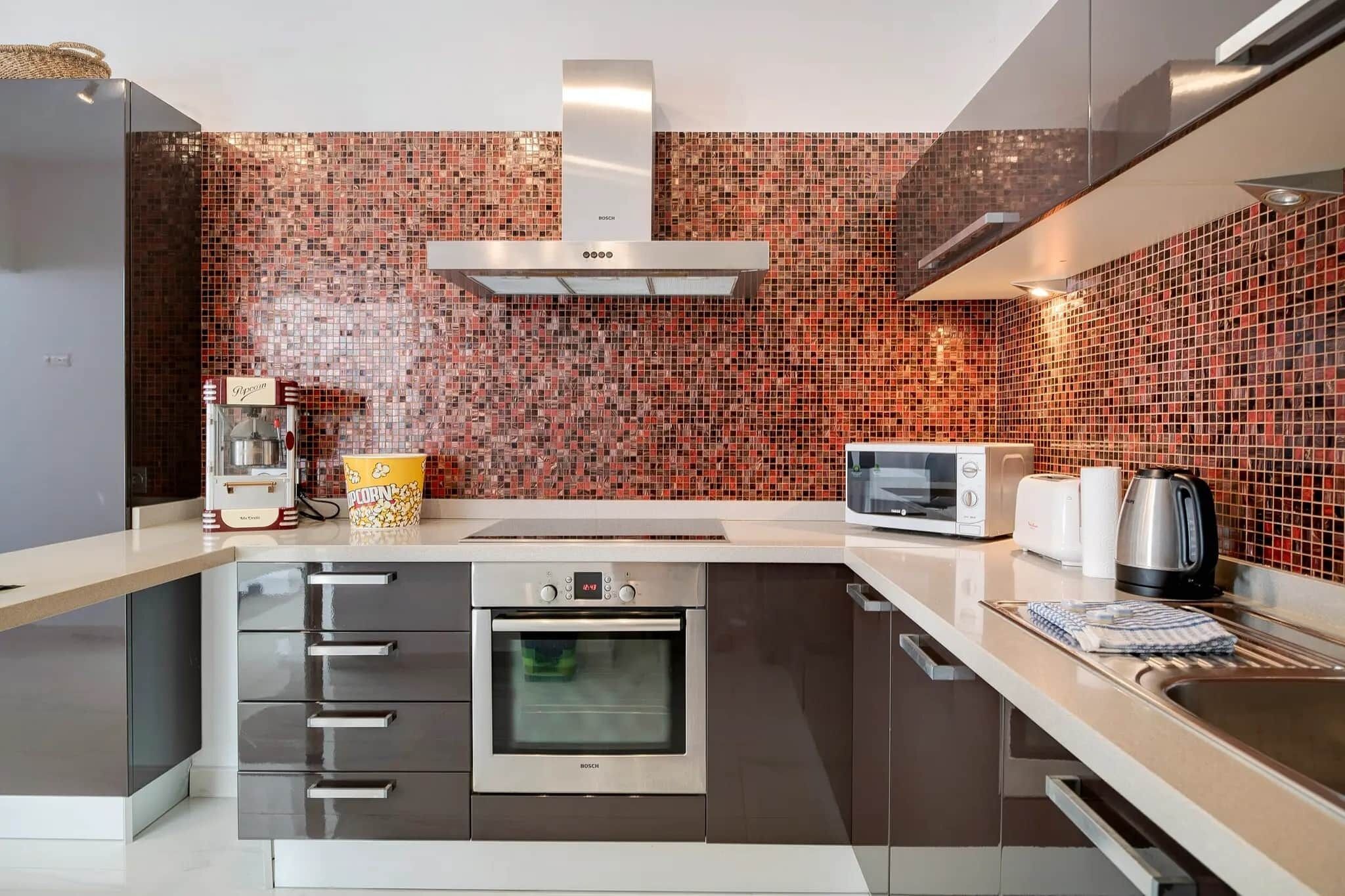 Una cocina moderna con horno Bosch, microondas, hervidor y máquina para palomitas de maíz.