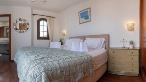 A bedroom with a bed, a dresser, a mirror, a window with curtains, and wall-mounted lights. - Luxury villa with a stunning sea view (Playa Blanca)