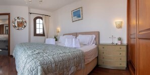 A bedroom with a bed, a dresser, a mirror, a window with curtains, and wall-mounted lights. - Luxury villa with a stunning sea view (Playa Blanca)