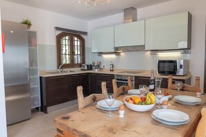 A modern kitchen with a central island, stainless steel appliances, and a dining area set for six. - Luxury villa with a stunning sea view (Playa Blanca)
