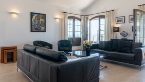 A modern living room with a black leather sofa, a glass coffee table, and a painting on the wall. - Luxury villa with a stunning sea view (Playa Blanca)