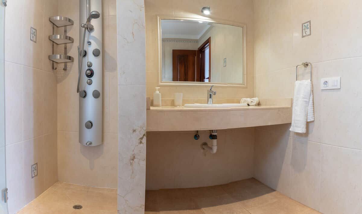 Ein Badezimmer mit Dusche, Waschbecken, Spiegel und Handtuchhalter.