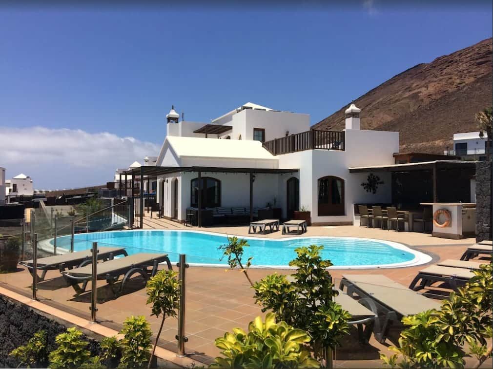 Un bâtiment moderne doté d’une piscine, d’un espace extérieur aménagé et offrant une vue sur un paysage montagneux.