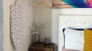 A bedroom with a bed, a bedside table, a wall-mounted shelf, and a colorful abstract painting. - Studio apartment 7 minutes from the airport in Carolina (Carolina)