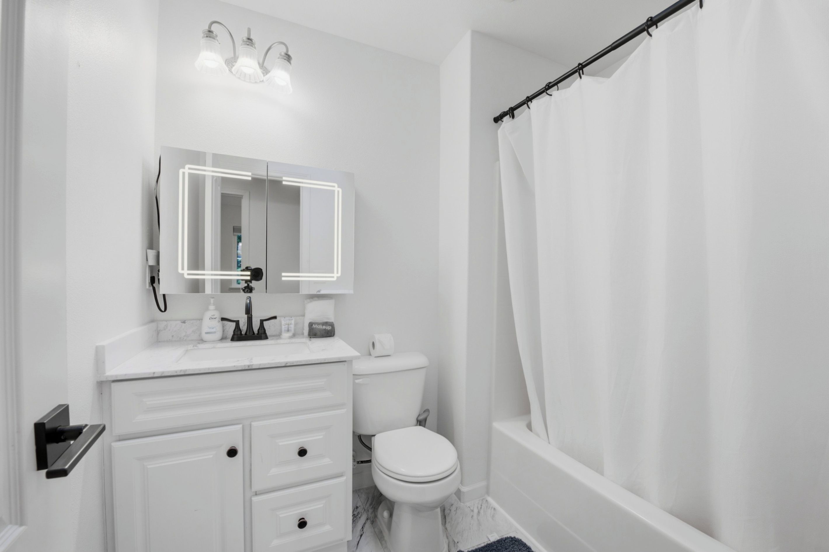 A bathroom with a toilet, sink, mirror, and shower curtain.