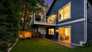 Een modern huis met twee verdiepingen, een overdekte patio, gazon en terras.