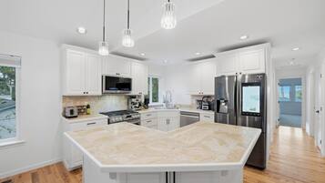 A modern kitchen with white cabinetry, stainless steel appliances, and a large island.