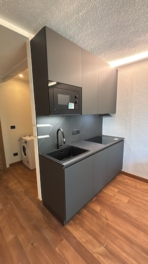 A compact kitchen with a built-in microwave, a sink, and a washing machine in the corner. - San Sicario Alto, Renovated Two-Bedroom Apartment, Ski-In/Ski-Out, Wi-Fi, View of the Alps (Cesana Torinese)