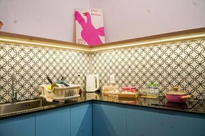 Una cocina con salpicadero decorativo, un lavamanos y diversos utensilios.
