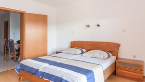 Un dormitorio con cama, cabecero de madera, mesitas de noche y una puerta que da a otra habitación.