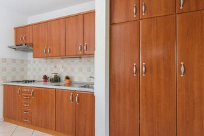 A kitchen with wooden cabinets, a stainless steel sink, and a range hood. - A2 – apartment Robi with shared heated pool & balcony, near the beach (Seget Vranjica)