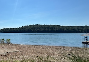 A calm lake with a dock and a small building on the right. - Luxury Lakefront Escape on Beaver Lake - Sleeps the Whole Crew (Rogers)
