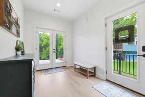 A clean, modern entryway with a bench, double doors leading to a balcony, and a small potted plant. - Luxury Lakefront Escape on Beaver Lake - Sleeps the Whole Crew (Rogers)