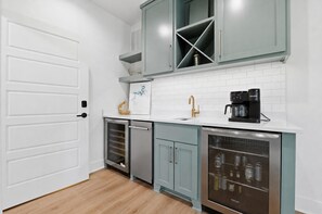 A modern kitchen with a white door, light blue cabinets, a stainless steel dishwasher, and a coffee maker on the counter. - Luxury Lakefront Escape on Beaver Lake - Sleeps the Whole Crew (Rogers)