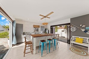 Eine moderne Küche mit einer Holztheke, Barhocker und einem Deckenventilator.